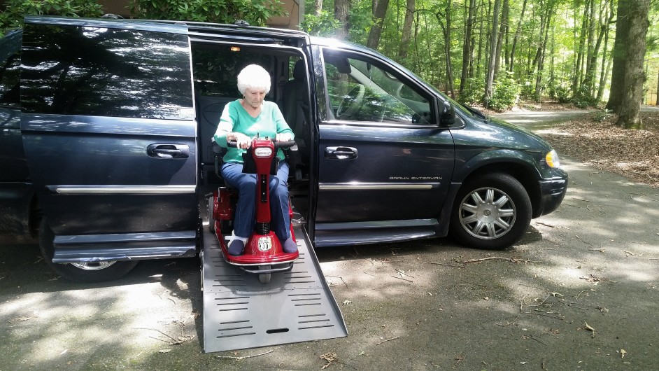 Donna anziana esce da auto con sedia motorizzata