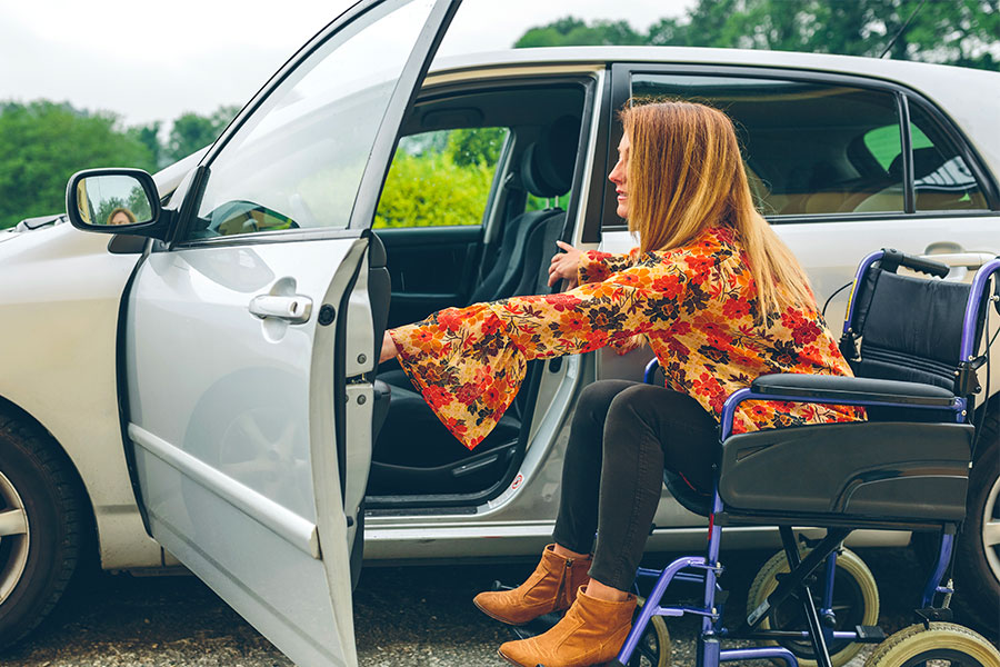 Donna disabile su sedia a rotelle entra in auto